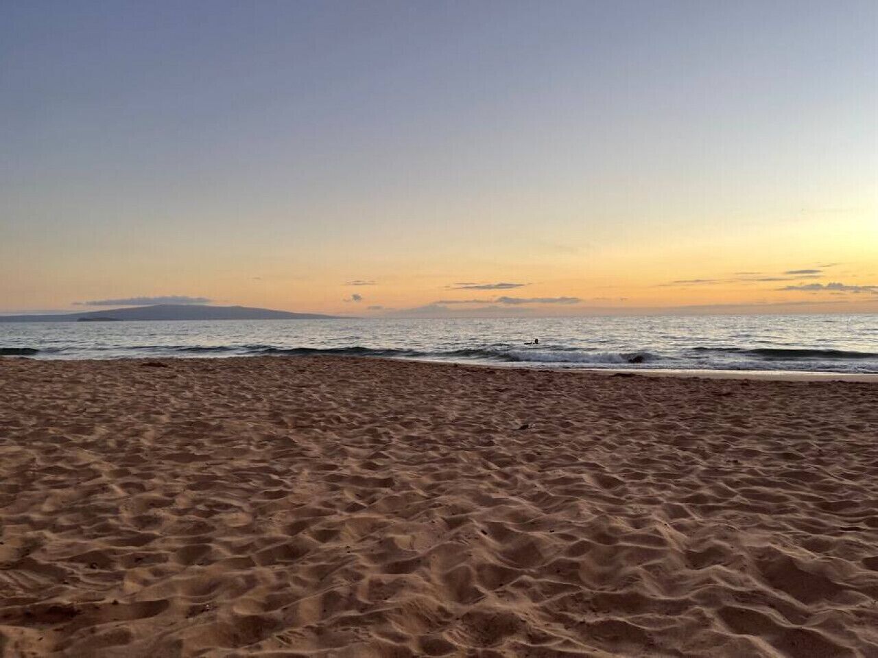 A sandy beach with gentle waves and a clear sky.