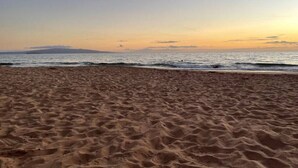 Ein sandiger Strand mit sanften Wellen und blauem Himmel.