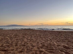 Ein sandiger Strand mit sanften Wellen und blauem Himmel.