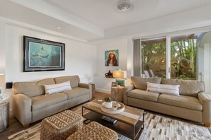 Una sala de estar moderna con dos sofás, una mesa de centro y un ventanal con vistas a zonas verdes.