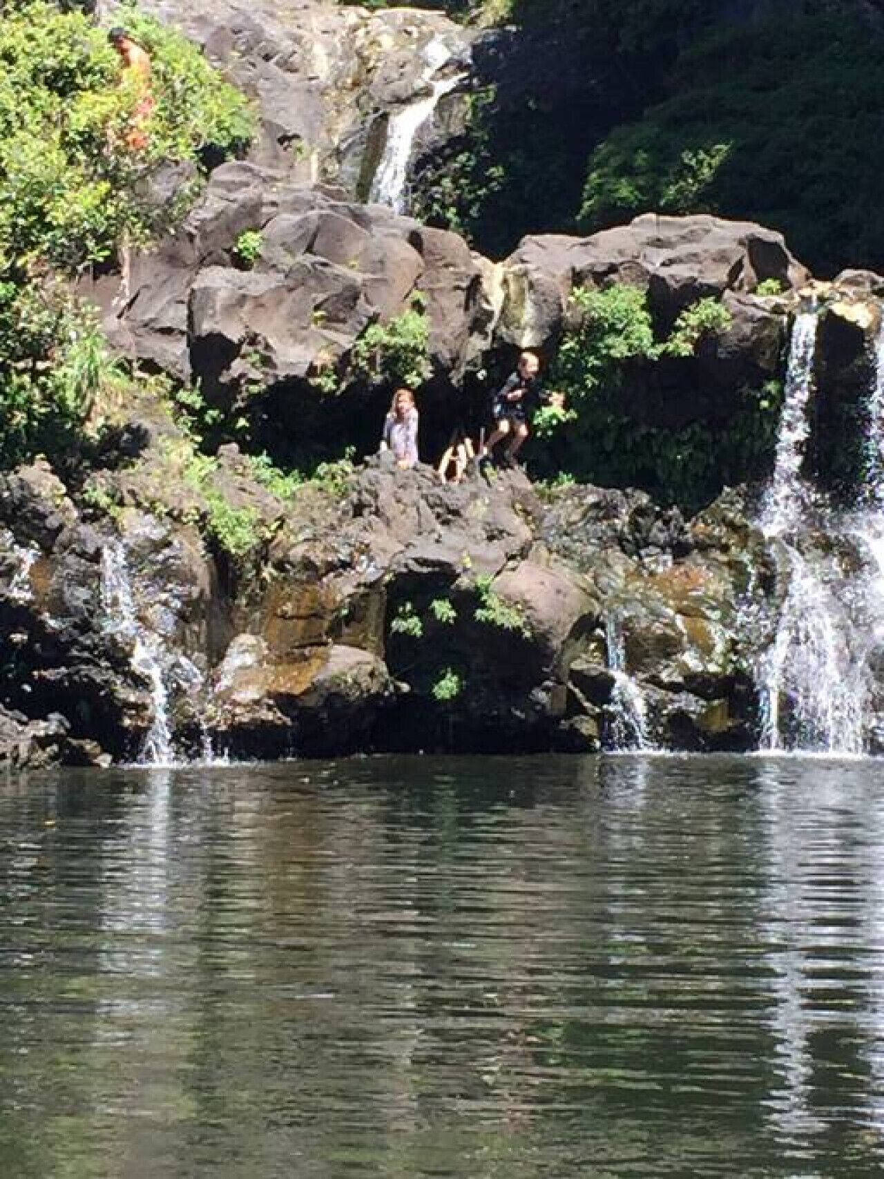 A natural rock formation with a waterfall and a body of water below.