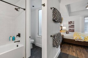 Ein modernes Badezimmer mit Dusche, Toilette und einem Bett mit einem gemusterten Bettzeug.
