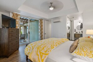 Une chambre à coucher comprenant un lit, une commode, un téléviseur et une porte-fenêtre coulissante donnant sur un balcon.