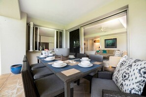 A dining area with a table set for four, a sofa, and a large window.