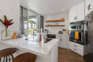 Een moderne keuken met witte kastjes, een marmeren aanrechtblad en roestvrijstalen apparatuur.