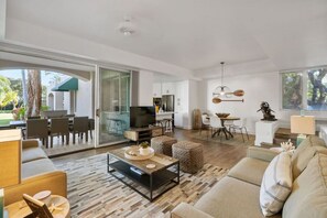 Een ruime woonkamer met een flatscreen televisie, een eettafel en een bank.