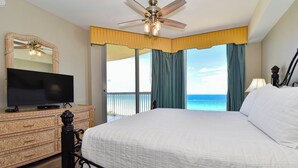 A hotel room with a large bed, a television on a dresser, a ceiling fan, and a view of the ocean. - Beachfront condo w/tile, hardwoods, & a private balcony! (Destin)