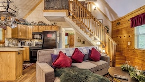 A cozy log cabin interior with a kitchen, dining area, and a staircase. - Amberwood, “Cozy Cabin Retreat in the Smokies – Comfort & Fun for All” (Sevierville)