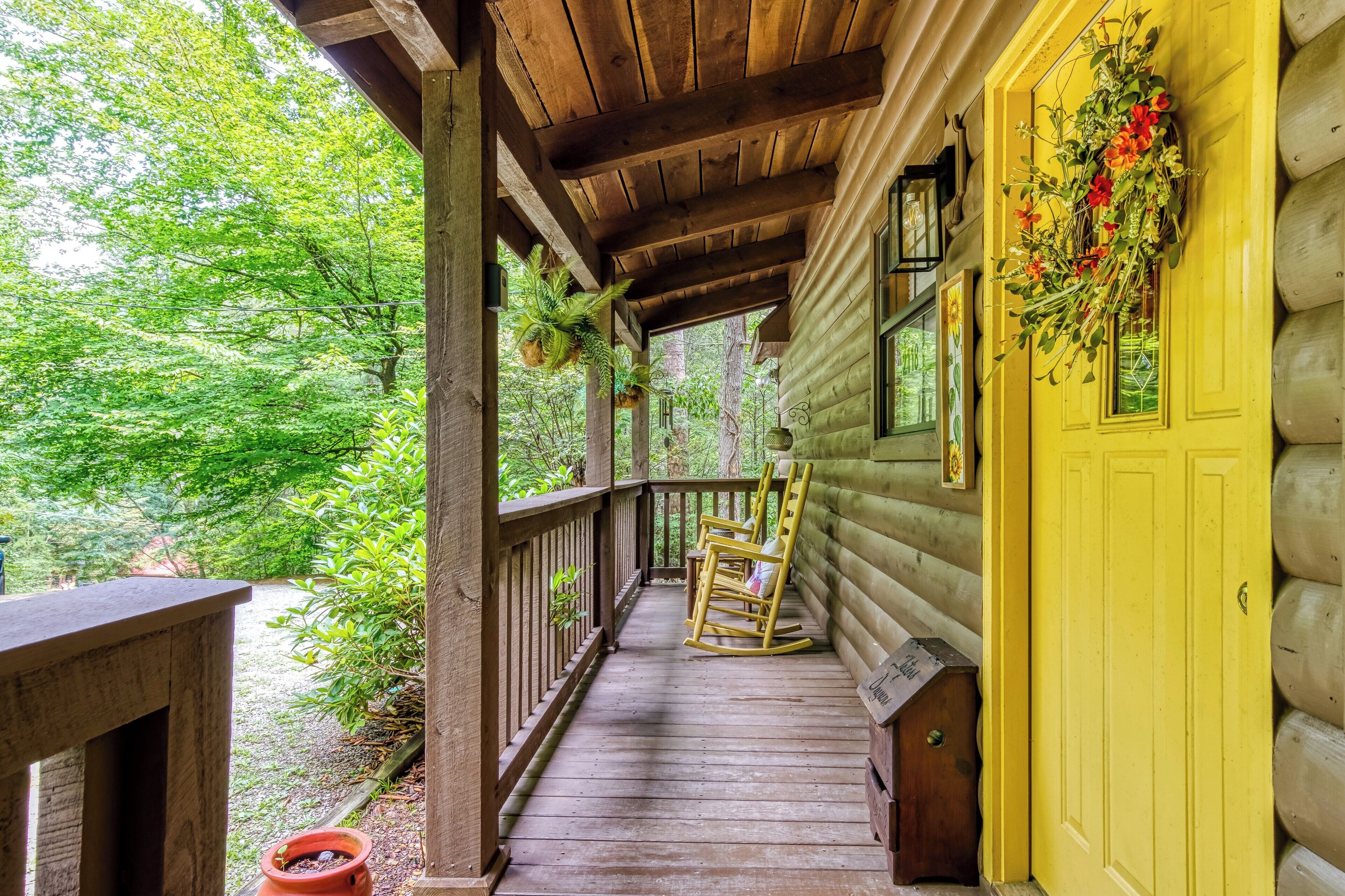 A wooden porch with a yellow door, rocking chairs, and a hanging plant.