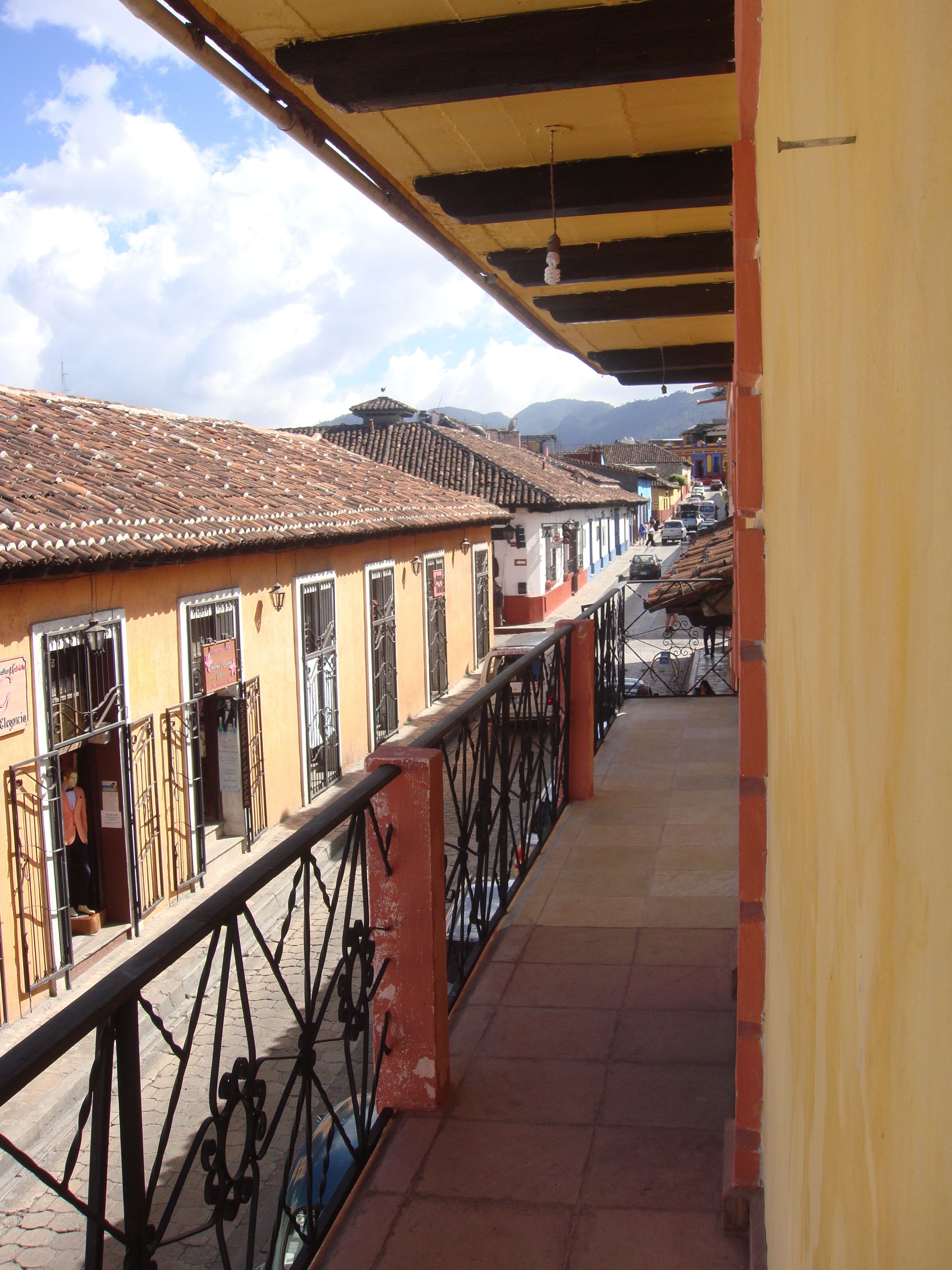 A balcony with a tiled roof overlooking a street with traditional buildings.