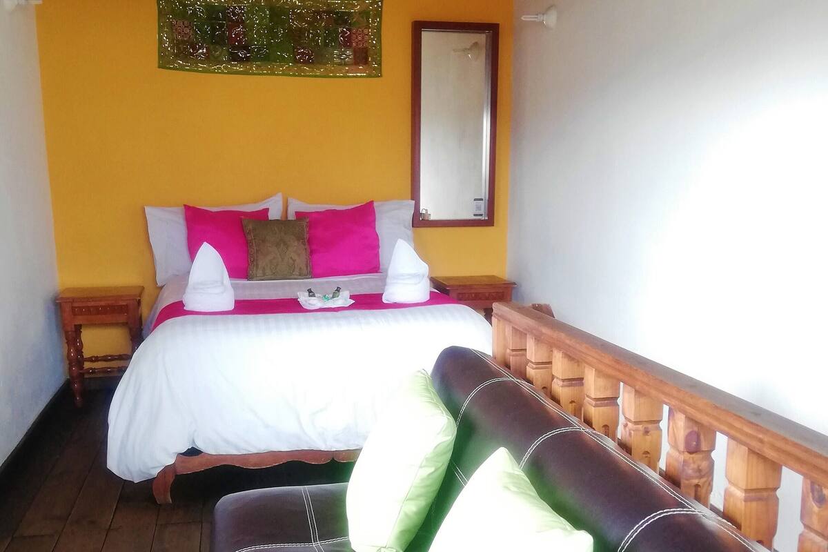 A room with a bed, a wooden bench, and a wooden railing.