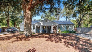 A single-story house with a front porch, surrounded by trees.