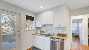 A kitchen with white cabinets, a stainless steel dishwasher, and a granite countertop.