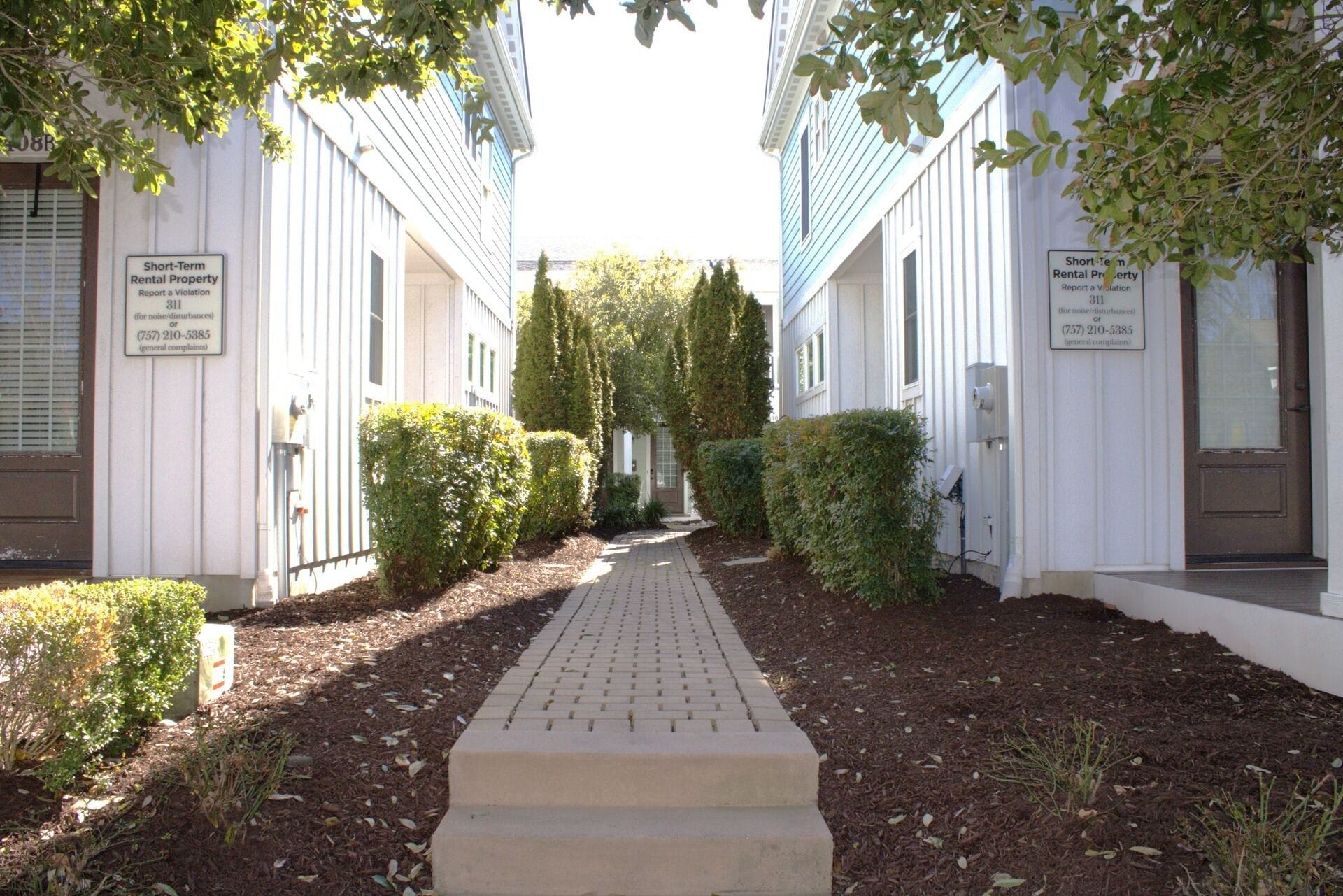 A pathway leading to a row of white buildings with short-term rental signs.