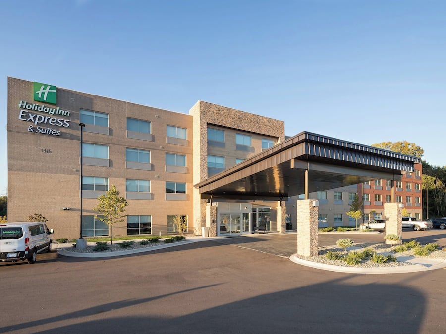 Een Holiday Inn Express & Suites gebouw met een overdekte ingang en een parkeerplaats.