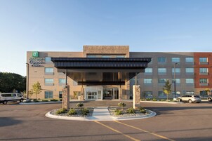Edificio Holiday Inn Express con una entrada moderna, zona de estacionamiento y cielo despejado.