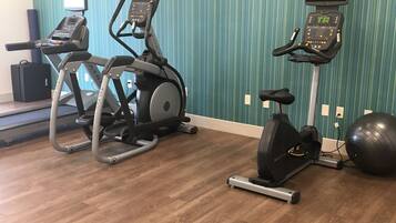 Un gimnasio con cintas de correr, elípticas y una bicicleta estática.