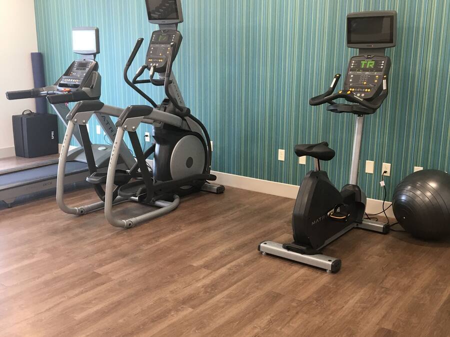 Un gimnasio con cintas de correr, elípticas y una bicicleta estática.