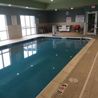 Una piscina interior con agua cristalina, marcas de profundidad y señalización de seguridad.