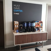 Una estación de café con varias máquinas de café y un cartel que dice 'NECESIDAD: CAFÉ'.