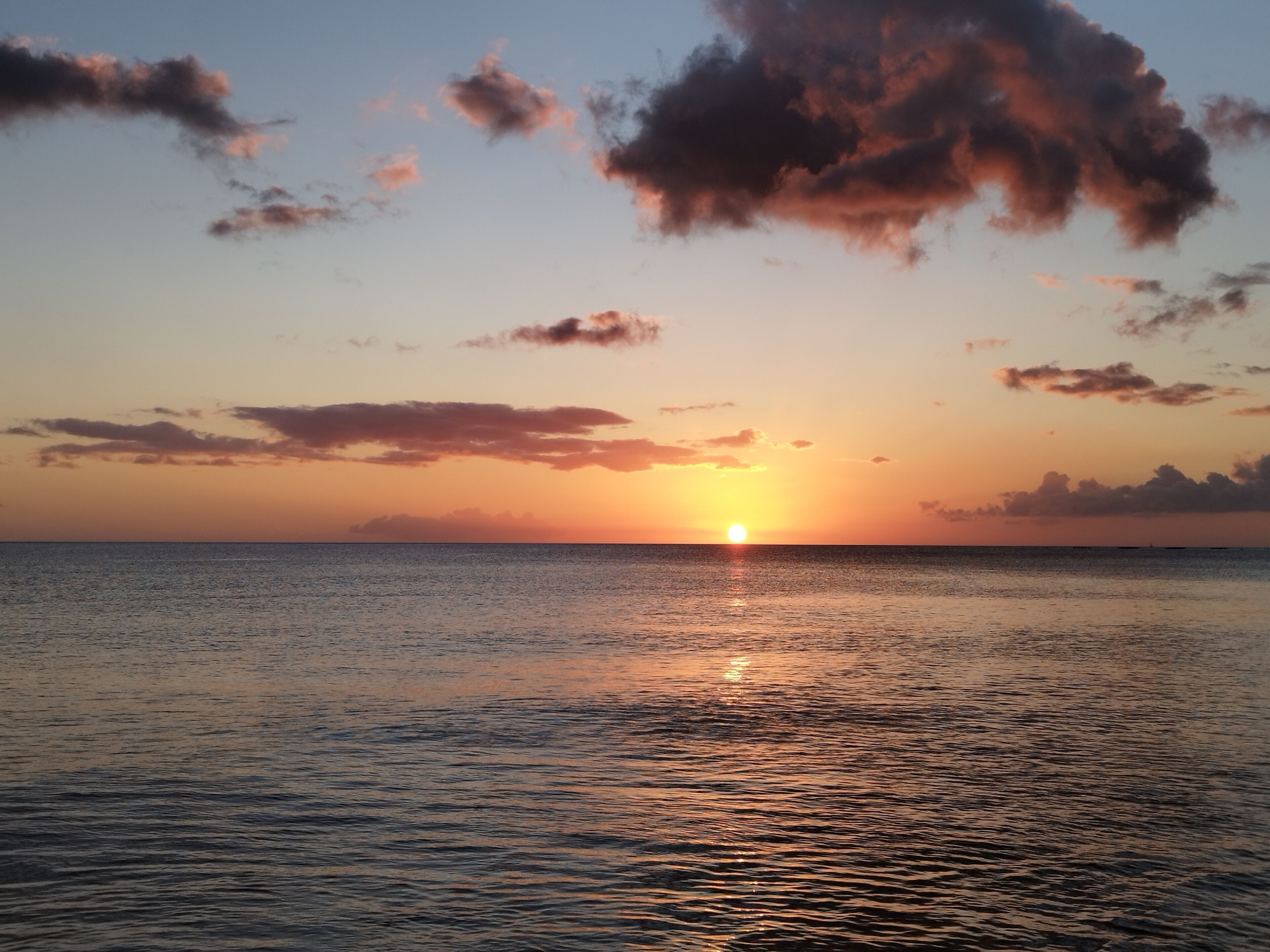 A sunset over a calm sea with a clear horizon.