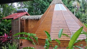 Een houten constructie met rieten dak, omringd door weelderig groen.
