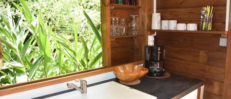 A kitchen with a white sink, wooden shelves, and a coffee maker.