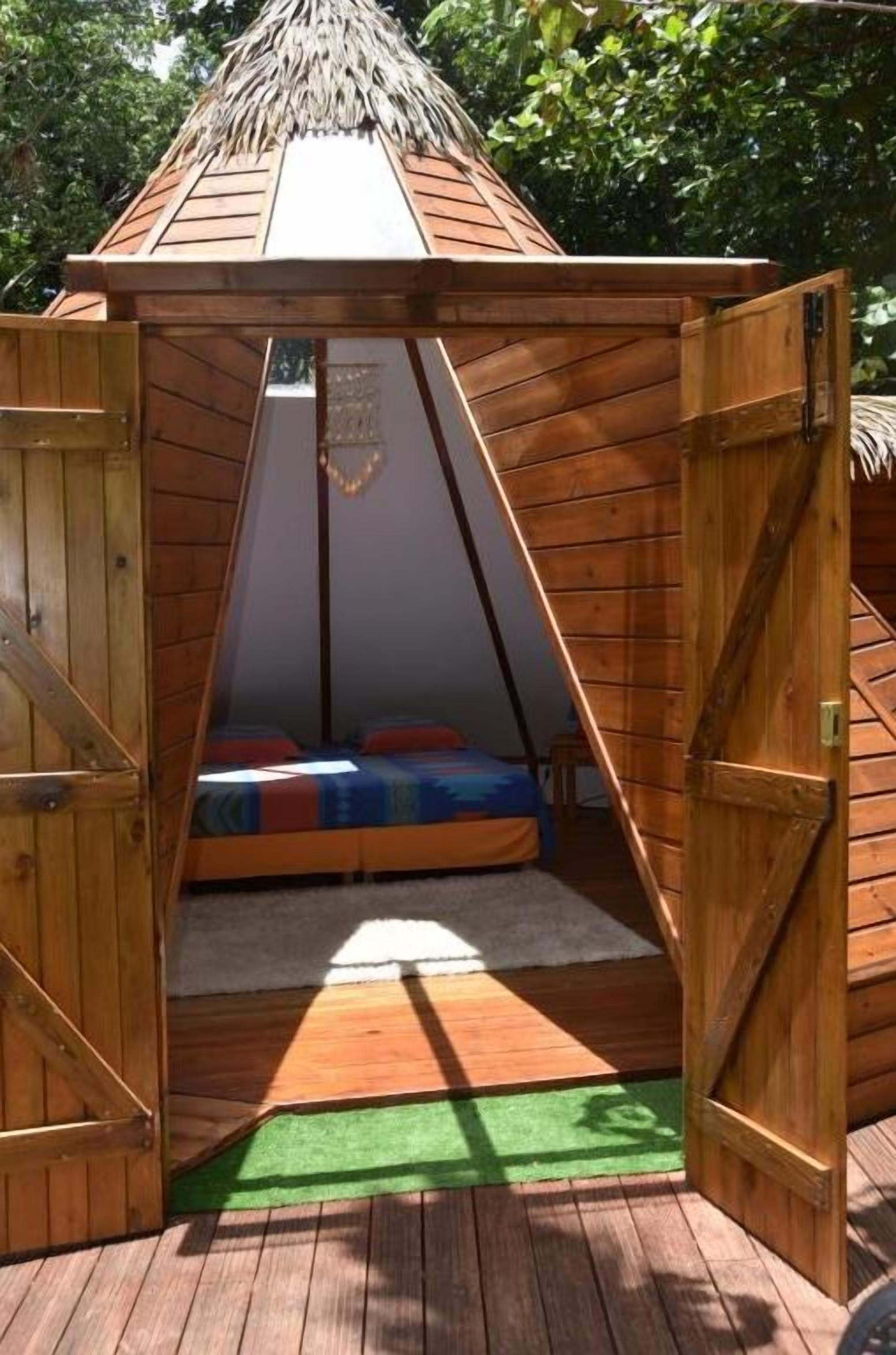A wooden A-frame structure with a bed inside.