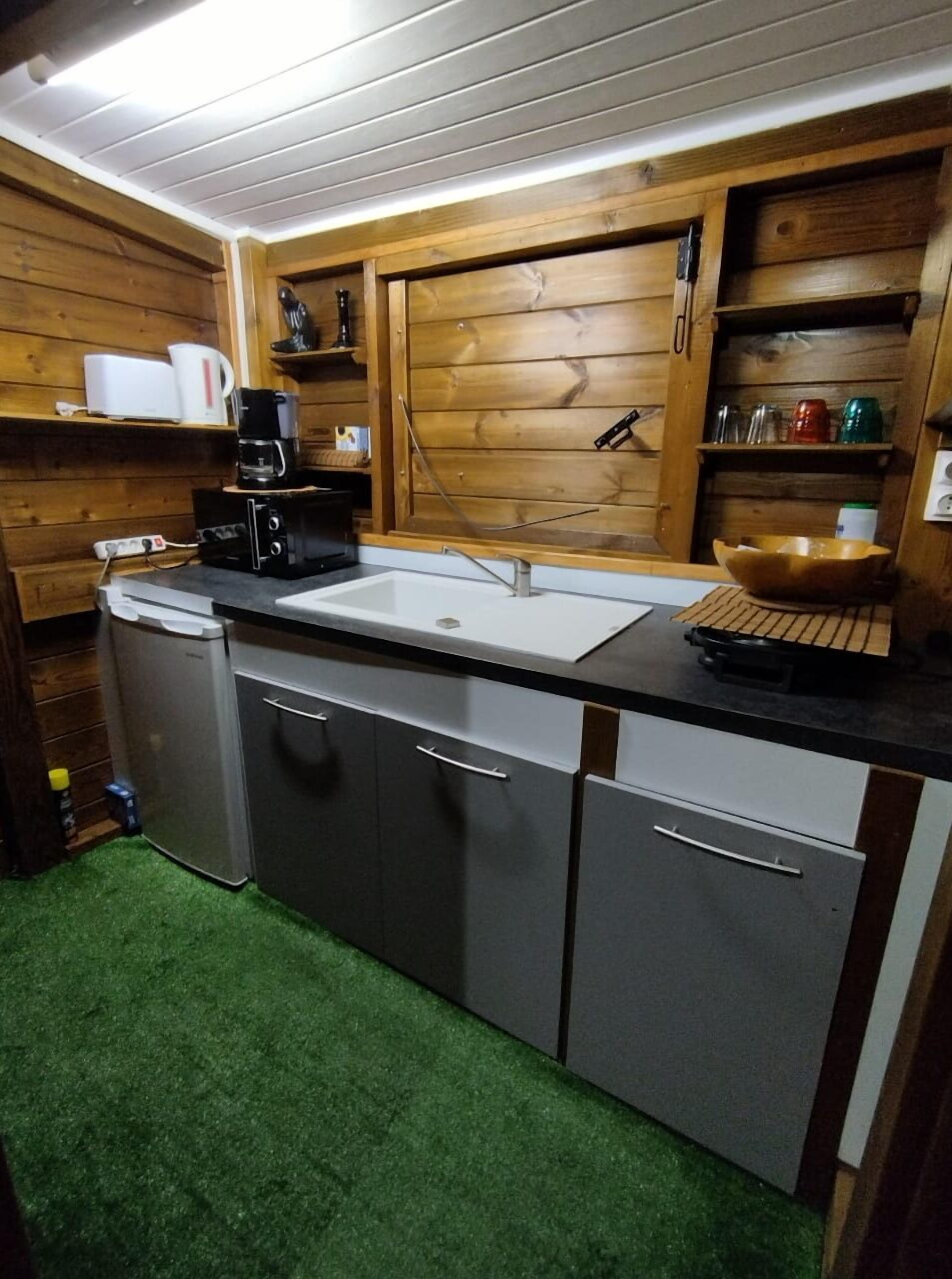 Cocina compacta con un lavamanos, una cafetera y un tazón sobre la encimera.