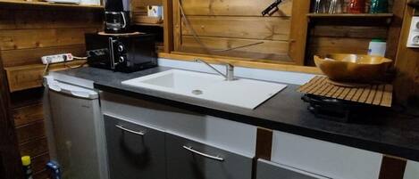 Cocina compacta con un lavamanos, una cafetera y un tazón sobre la encimera.