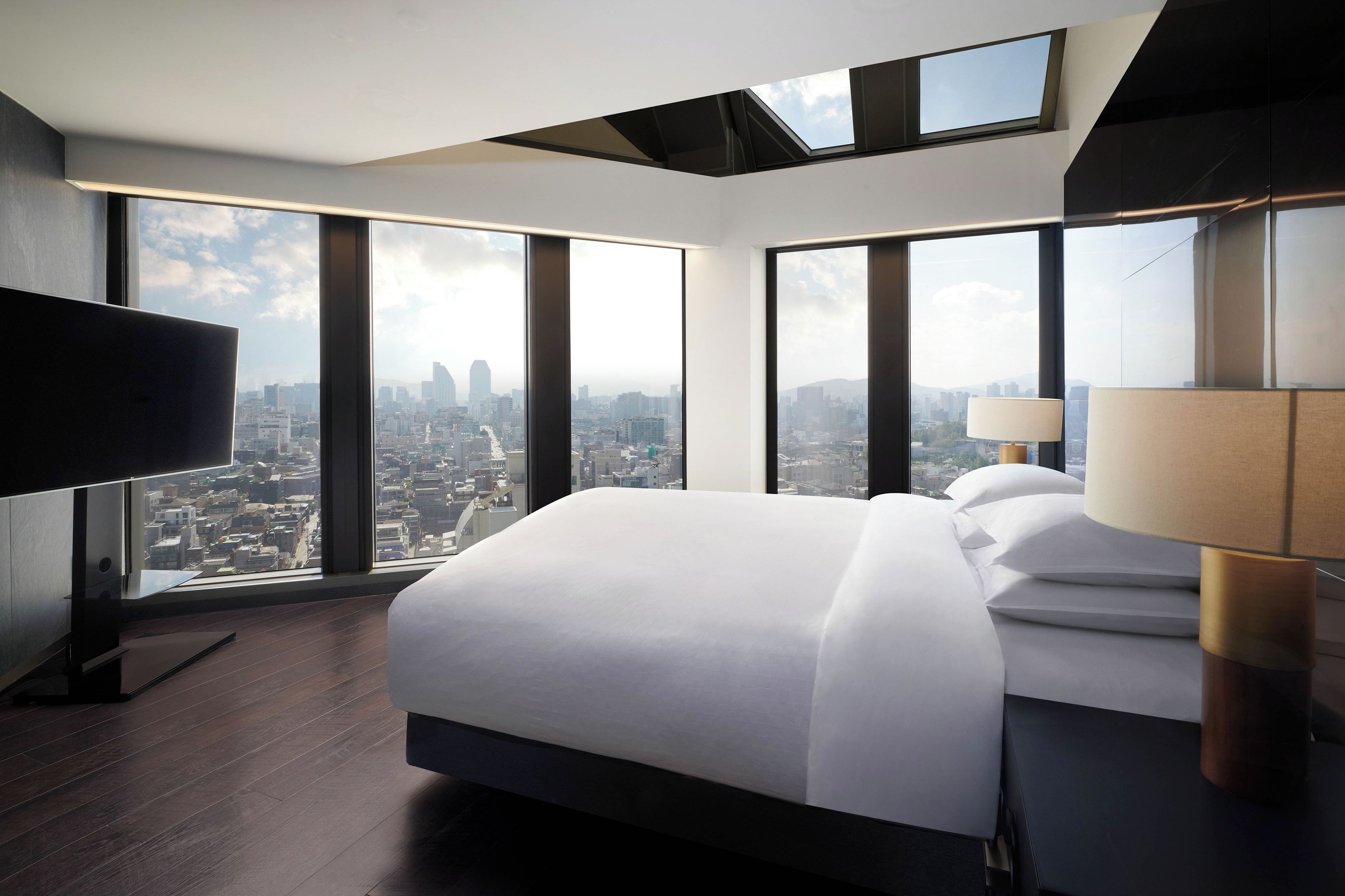 Habitación de hotel moderna con una cama grande, televisor de pantalla plana y vistas a la ciudad.