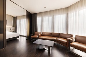 A modern hotel room with a large bed, a leather sofa, a glass coffee table, and a large window with sheer curtains. - Four Points by Sheraton Seoul Gangnam (Seoul)