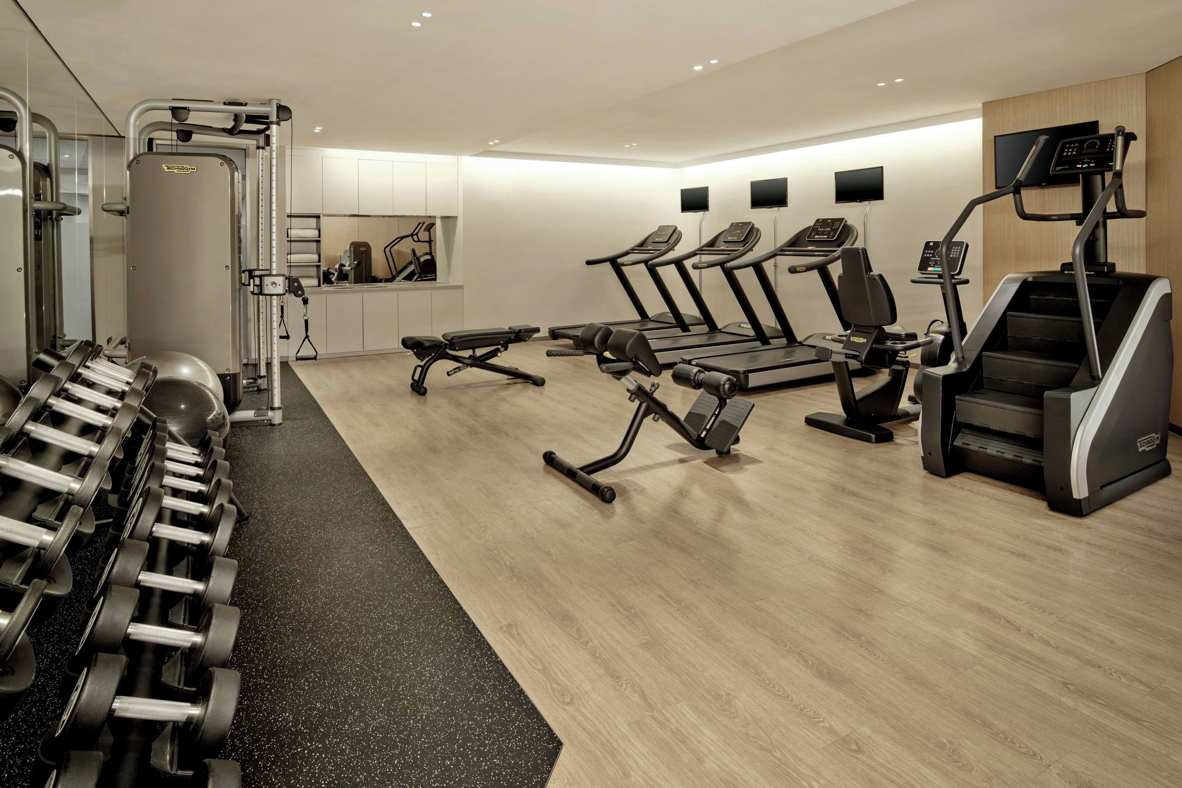A modern gym with treadmills, elliptical machines, and free weights.