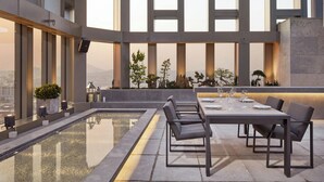 Un espacio moderno al aire libre para comer con piscina, asientos y plantas en macetas.