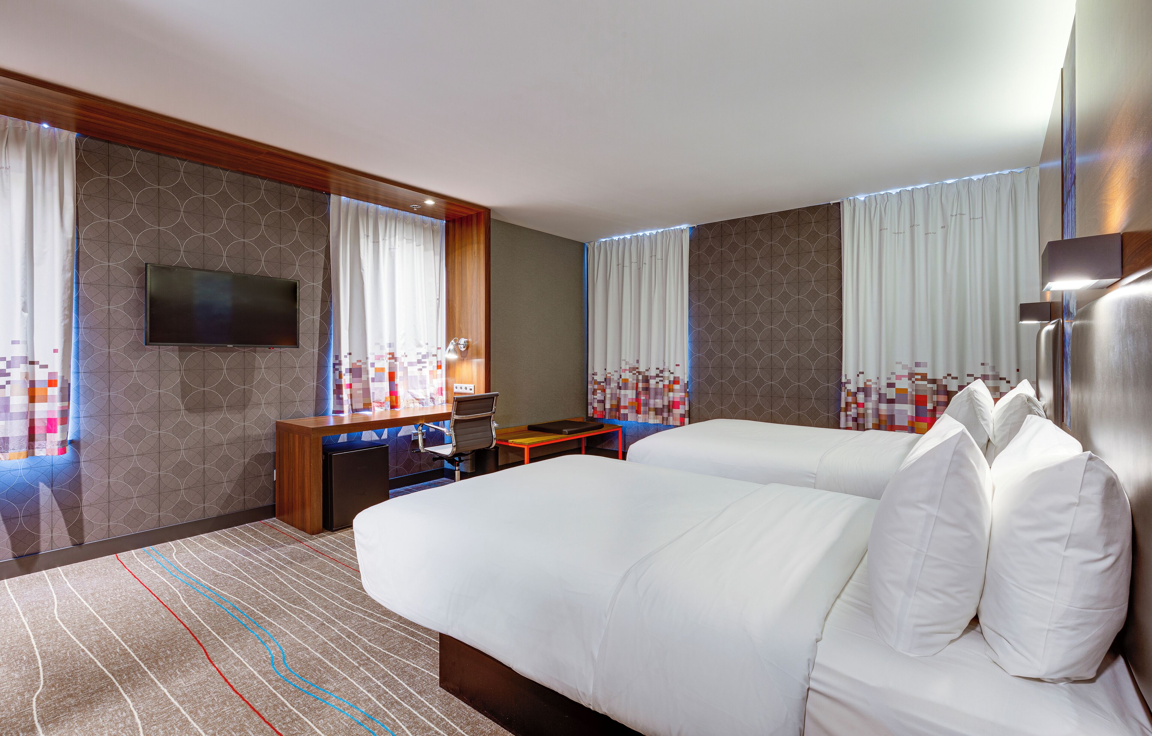 Une chambre d’hôtel avec un grand lit, un bureau, une télévision et un minibar.