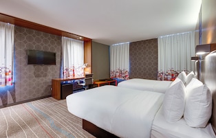 Een hotelkamer met een groot bed, een bureau, een televisie en een minibar.