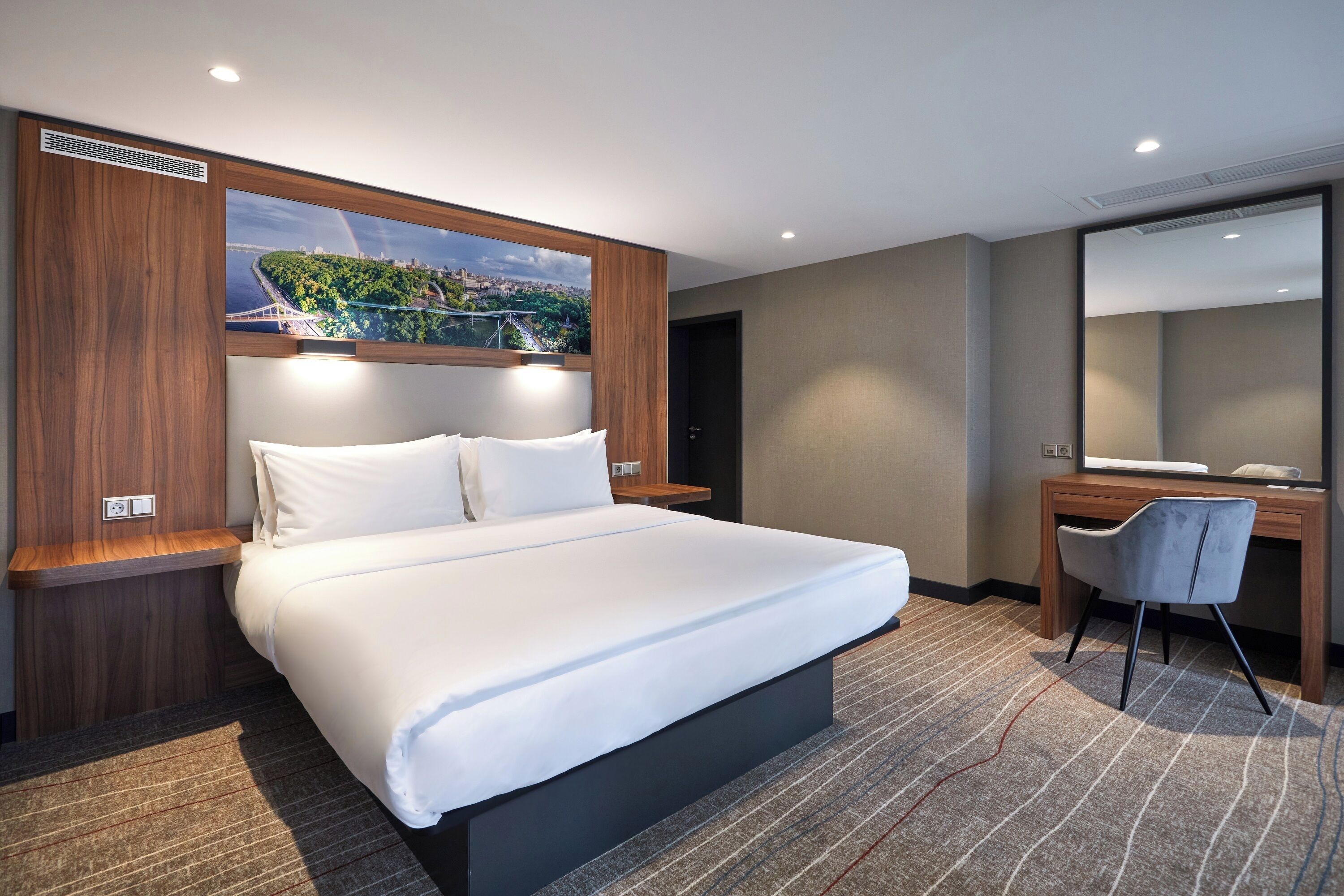 Ein modernes Hotelzimmer mit einem großen Bett, einem Schreibtisch und Blick auf die Stadt.
