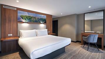 Ein modernes Hotelzimmer mit einem großen Bett, einem Schreibtisch und Blick auf die Stadt.