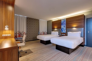 Een hotelkamer met twee bedden, een bureau en een stoel.