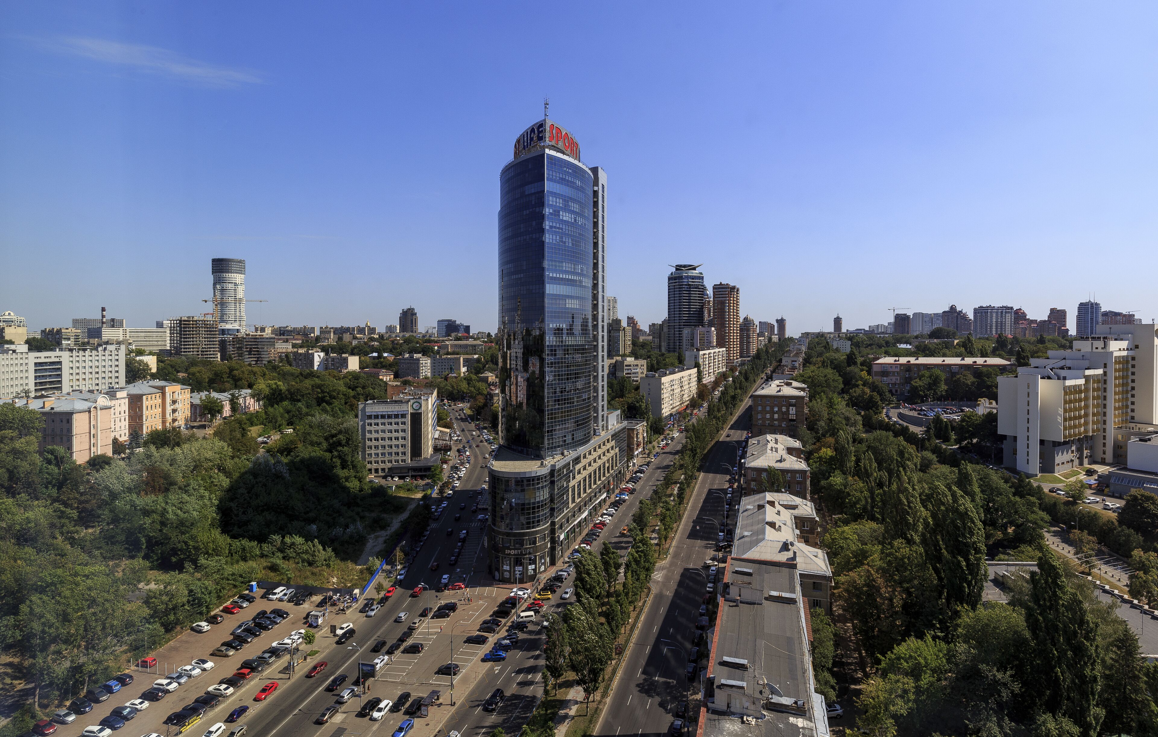 A high-rise hotel with a modern glass facade, surrounded by a mix of urban buildings and greenery.