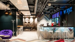 A modern bar area with a herringbone-patterned wall, bar stools, and a neon sign. - Sky Loft Hotel by Rixwell (Kyiv)