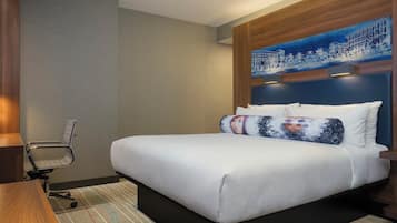 Een hotelkamer met een groot bed, een bureau en een stoel.