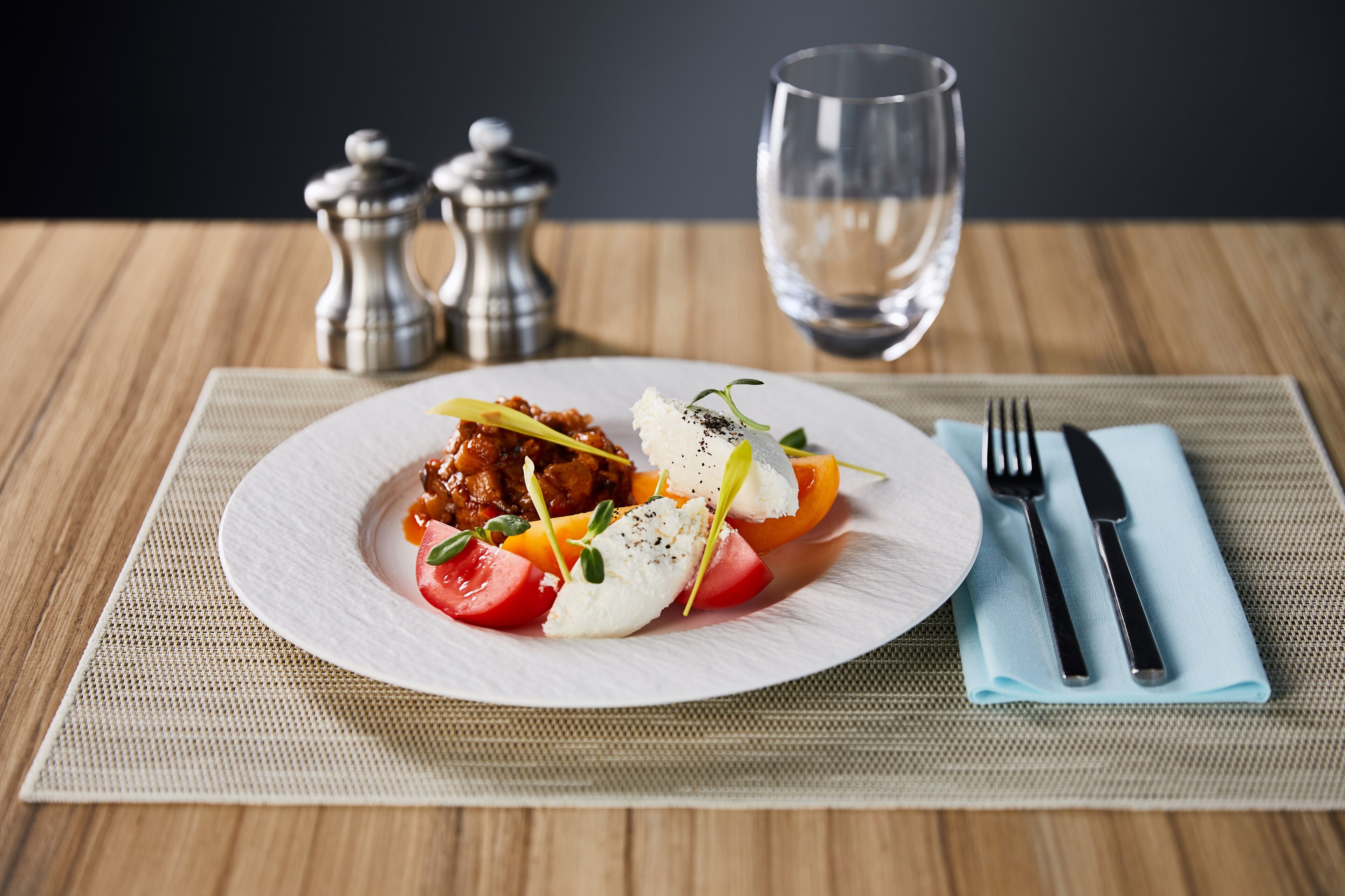 Un plato de comida con un tenedor y un cuchillo sobre un mantel individual.