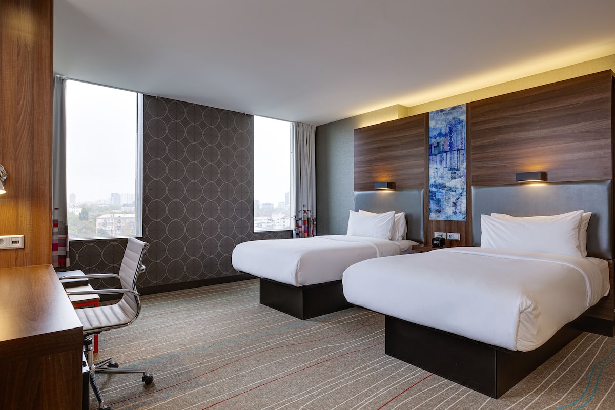 Habitación de hotel con dos camas, un escritorio y una silla.