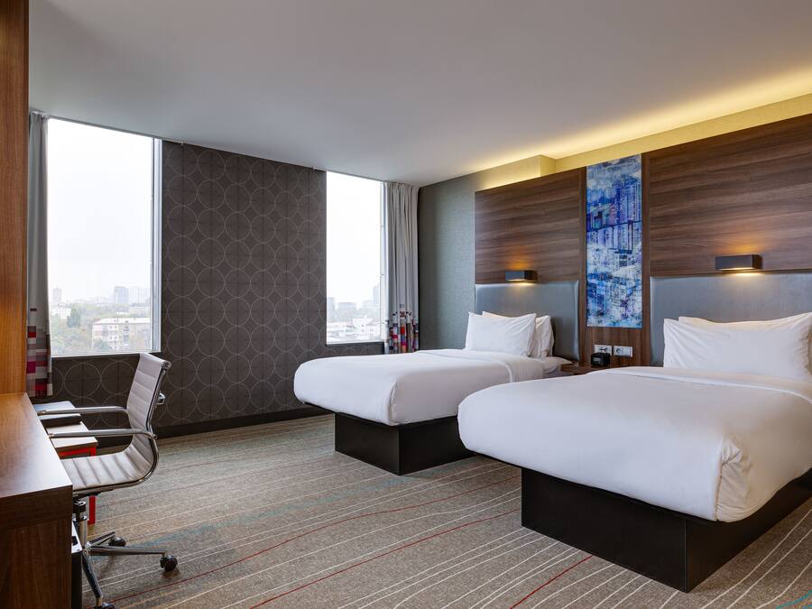 A hotel room with two beds, a desk, and a chair.