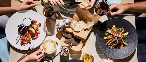 Una mesa de comedor con varios platos, incluyendo una fuente de comida, una taza de café y un vaso de agua.
