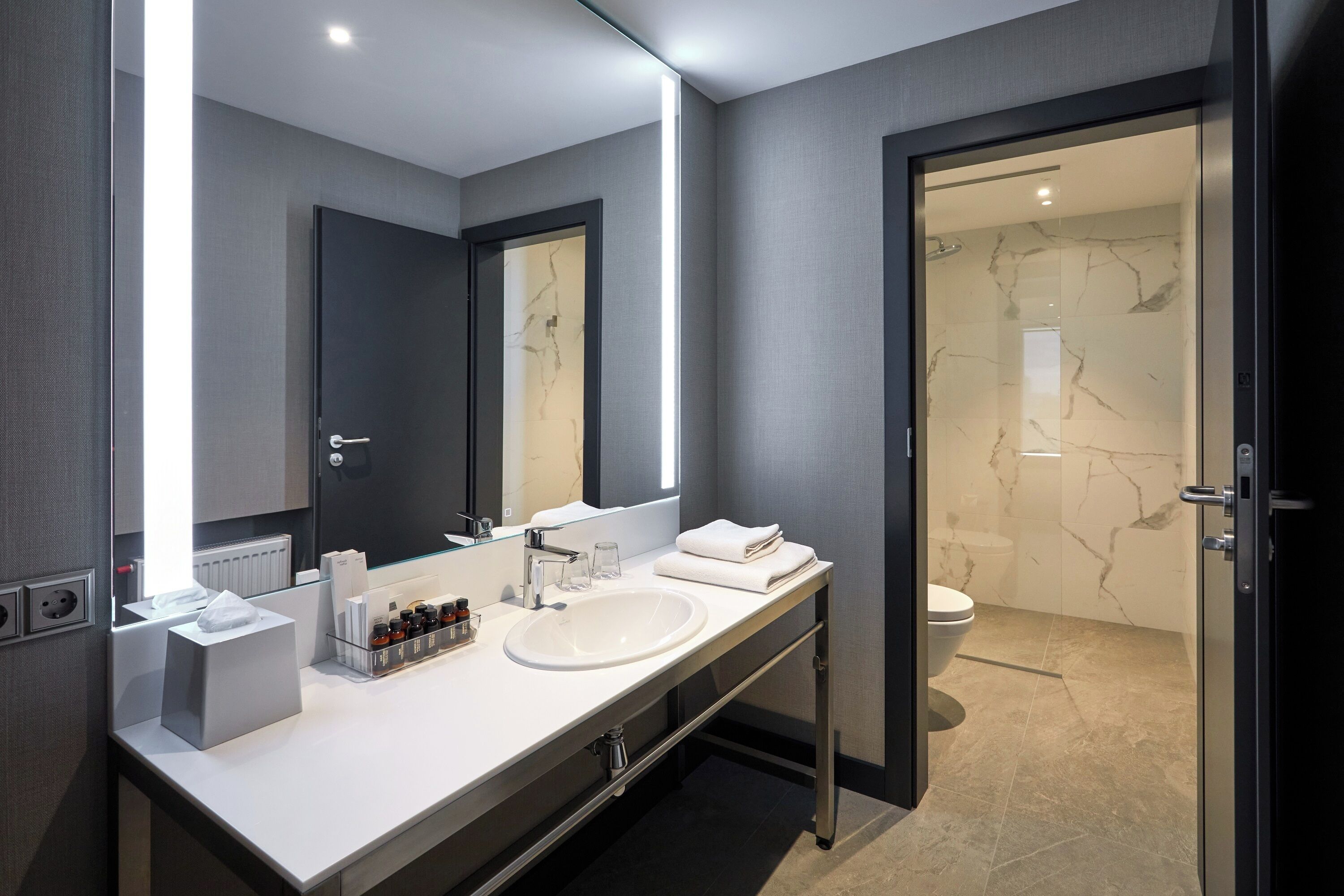 Een moderne badkamer met een grote spiegel, twee wastafels en een douche.