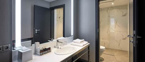 A modern bathroom with a large mirror, two sinks, and a shower area.