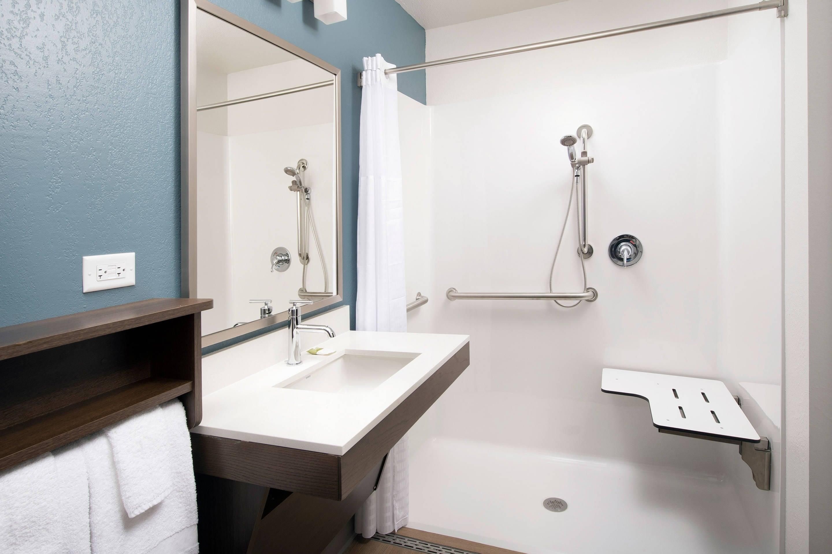 A modern bathroom with a shower, a sink, and a mirror.