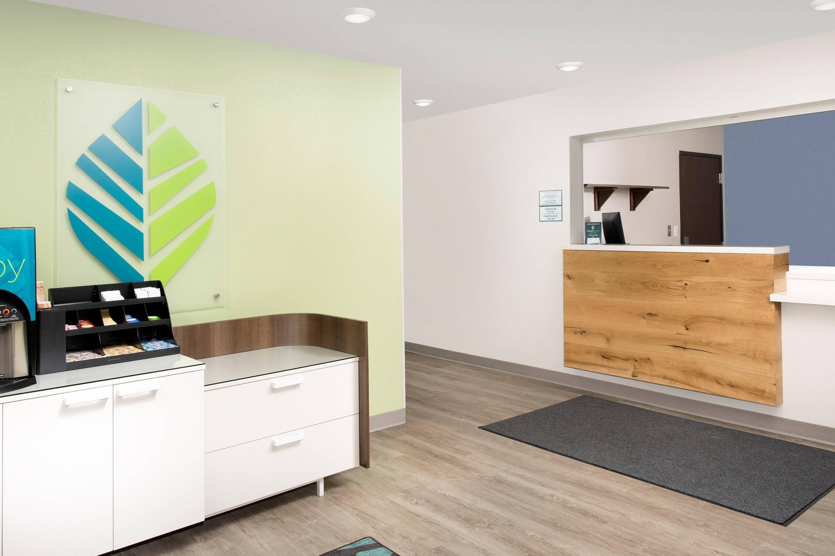 Zona de recepción con un mostrador, una máquina de café, un espejo en la pared y un panel de madera.